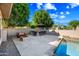 Outdoor kitchen and fire pit with seating by pool; perfect for entertaining guests at 2565 N 141St Ln, Goodyear, AZ 85395