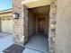 Covered front entry showcasing stone columns and a solid wood front door at 2727 N Acacia Way, Buckeye, AZ 85396