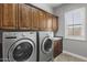 Spacious laundry room with front-load washer and dryer, wooden cabinets, and tile flooring at 31703 N 15Th Dr, Phoenix, AZ 85085