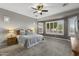 Spacious main bedroom with large bay windows, ceiling fan, neutral carpet, and a wooden bed frame at 31703 N 15Th Dr, Phoenix, AZ 85085