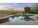 Tranquil pool area with rock waterfall feature, lush landscaping, and a cozy fire pit at 31703 N 15Th Dr, Phoenix, AZ 85085