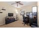 Well-lit bedroom designed as a home office with a ceiling fan, a desk with a chair, a TV and shelves at 3207 E Behrend Dr, Phoenix, AZ 85050