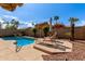 Private backyard pool with palm trees, lounge chairs, and a sun umbrella on a sunny day at 3207 E Behrend Dr, Phoenix, AZ 85050