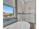 Bright bathroom features a luxurious tub, tiled walk-in shower, and a large window providing great natural light at 3421 S 256Th Ave, Buckeye, AZ 85326