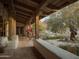 Covered backyard patio with wooden columns, red tile and views of desert landscaping at 4747 E Arroyo Verde Dr, Paradise Valley, AZ 85253