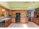 Well-lit kitchen featuring wood cabinets, black appliances and tile flooring at 5923 W Mauna Loa Ln, Glendale, AZ 85306