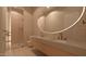 Modern bathroom featuring a frameless glass shower, and double sink vanity with large, lighted round mirror at 6649 E Ocotillo Rd, Paradise Valley, AZ 85253