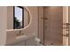 Modern bathroom featuring a walk-in shower with glass doors, and a circular mirror with vanity lighting at 6649 E Ocotillo Rd, Paradise Valley, AZ 85253