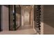 Bright hallway with light stone walls and floors leads to a glass-enclosed wine storage at 6649 E Ocotillo Rd, Paradise Valley, AZ 85253