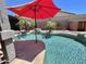 Backyard pool featuring a unique rock waterfall, surrounding palm trees, and red umbrella at 723 S Weaver Dr, Apache Junction, AZ 85120