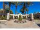 Elegant community entrance featuring palm trees, manicured landscaping, and a decorative stone design at 7272 E Gainey Ranch Rd # 117, Scottsdale, AZ 85258