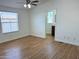 Bright bedroom with wood-style flooring, fan and light fixture, and views into the connected bathroom at 7300 N 51St Ave # G102, Glendale, AZ 85301