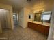 Well-lit bathroom with a double sink vanity, tile flooring, and a separate shower and toilet room at 8006 W Gibson Ln, Phoenix, AZ 85043