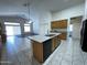 Open kitchen features tile flooring, a kitchen island with a sink, and natural wood cabinetry at 8006 W Gibson Ln, Phoenix, AZ 85043