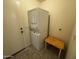 Functional laundry room with stacked washer/dryer, tile floors, bench seat, and door to the exterior at 8006 W Gibson Ln, Phoenix, AZ 85043