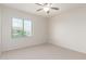 A bright bedroom with neutral carpet, a ceiling fan, and a window with blinds at 881 E Boston St, Gilbert, AZ 85295