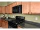 Close-up of a kitchen with a black stove, microwave, and wooden cabinets at 11626 E Yeager Cyn, Gold Canyon, AZ 85118