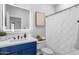 Well-lit bathroom with white countertop, blue cabinets, square mirror, and white patterned shower curtain at 1526 E Glacier Pl, Chandler, AZ 85249