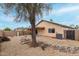 Landscaped backyard with desert features, rock detail, mature tree, and covered patio at 15835 W Woodlands Ave, Goodyear, AZ 85338