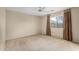 A spacious bedroom with neutral walls, carpeted floors, ceiling fan, and natural light from a window at 15835 W Woodlands Ave, Goodyear, AZ 85338