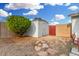 Backyard area showcasing a storage shed, vibrant bush, and a red wooden gate, complemented by gravel groundcover at 17616 N 20Th Dr, Phoenix, AZ 85023