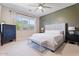 Relaxing main bedroom with neutral colors, bench, large window, and a ceiling fan at 1895 N 141St Ave, Goodyear, AZ 85395