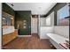 Chic bathroom with stylish wood vanity, freestanding tub, glass-enclosed shower, and elegant dark green walls at 20585 W Garden St, Buckeye, AZ 85396