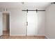 Bedroom with light gray walls and wood laminate flooring features a sliding barn door at 2127 W San Miguel Ave, Phoenix, AZ 85015