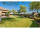 Backyard featuring a lush green lawn, mature trees, a pool, and an outdoor fireplace with seating at 2735 E Flower Ct, Gilbert, AZ 85298
