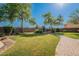 Backyard featuring a lush green lawn, mature trees, and a cozy outdoor fireplace seating area at 2735 E Flower Ct, Gilbert, AZ 85298