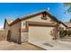 Side view of single-story home featuring a two-car garage with stone accents and tidy landscaping at 3029 N 83Rd Ln, Phoenix, AZ 85037