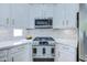 Modern kitchen with white cabinets, stainless steel appliances, and elegant marble backsplash at 3736 E Cotton Ct, Gilbert, AZ 85234