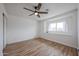 This bedroom features a large window, a modern ceiling fan, and wood-look floors at 4102 W Maryland Ave, Phoenix, AZ 85019