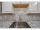 Close-up of the kitchen sink featuring granite counters, tile backsplash and modern faucet at 4102 W Maryland Ave, Phoenix, AZ 85019
