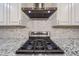 Close-up of a modern kitchen stove with stainless steel hood and tile backsplash at 4102 W Maryland Ave, Phoenix, AZ 85019