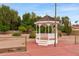 Close-up of a charming white gazebo set on a brick surface and surrounded by lush landscaping at 4107 E Fairview Cir, Mesa, AZ 85206