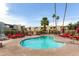 Beautiful community pool featuring palm trees, residential buildings, and red lounge chairs at 4630 N 68Th St # 221, Scottsdale, AZ 85251