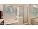 Bright bathroom featuring a bathtub, glass shower, and natural light from a window at 5502 N Ormondo Way, Litchfield Park, AZ 85340
