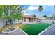 Charming backyard featuring artificial turf, a covered patio, desert landscaping, and mature trees at 5941 W Venus Way, Chandler, AZ 85226