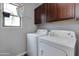 Laundry room featuring a side-by-side washer and dryer, and dark wood cabinets at 6907 S 8Th Dr, Phoenix, AZ 85041