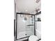 Bright shower with glass doors, neutral tiling, black hardware, a built-in shelf, and a window for natural lighting at 7272 W Crystal Rd, Glendale, AZ 85308