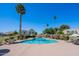 Community pool surrounded by green landscaping, palm trees, lounge seating and community buildings at 7830 E Valley Vista Dr, Scottsdale, AZ 85250