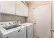 Functional laundry area with white appliances, cabinetry, and a door for convenience at 7930 W Wescott Dr, Glendale, AZ 85308