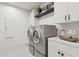 This laundry room has gray machines, white cabinets, shelving and light tile floor at 9265 N 115Th St, Scottsdale, AZ 85259