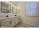 Bathroom featuring double sink vanity, mirrors, and plantation shutters at 9813 W Mcrae Way, Peoria, AZ 85382