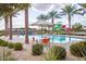 Beautiful pool area with tables, chairs, palm trees, and water slides, ideal for enjoying sunny days and outdoor gatherings at 9922 E Thunderbolt Ave, Mesa, AZ 85212
