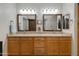 Bathroom with double vanity, wood cabinets, and framed mirrors, plus barn door to water closet at 11680 E Sahuaro Dr # 1059, Scottsdale, AZ 85259