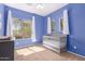 Bedroom with carpet, blue walls, neutral crib, and natural light from two windows at 1453 E Elgin Pl, Chandler, AZ 85225