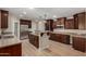 Spacious kitchen featuring dark wood cabinets, stainless steel appliances, an island and light countertops at 1535 E Kenwood St, Mesa, AZ 85203