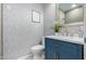 Bathroom showcases a blue vanity, a marble countertop, a framed mirror, and decorative wallpaper at 15753 W Christy Dr, Surprise, AZ 85379